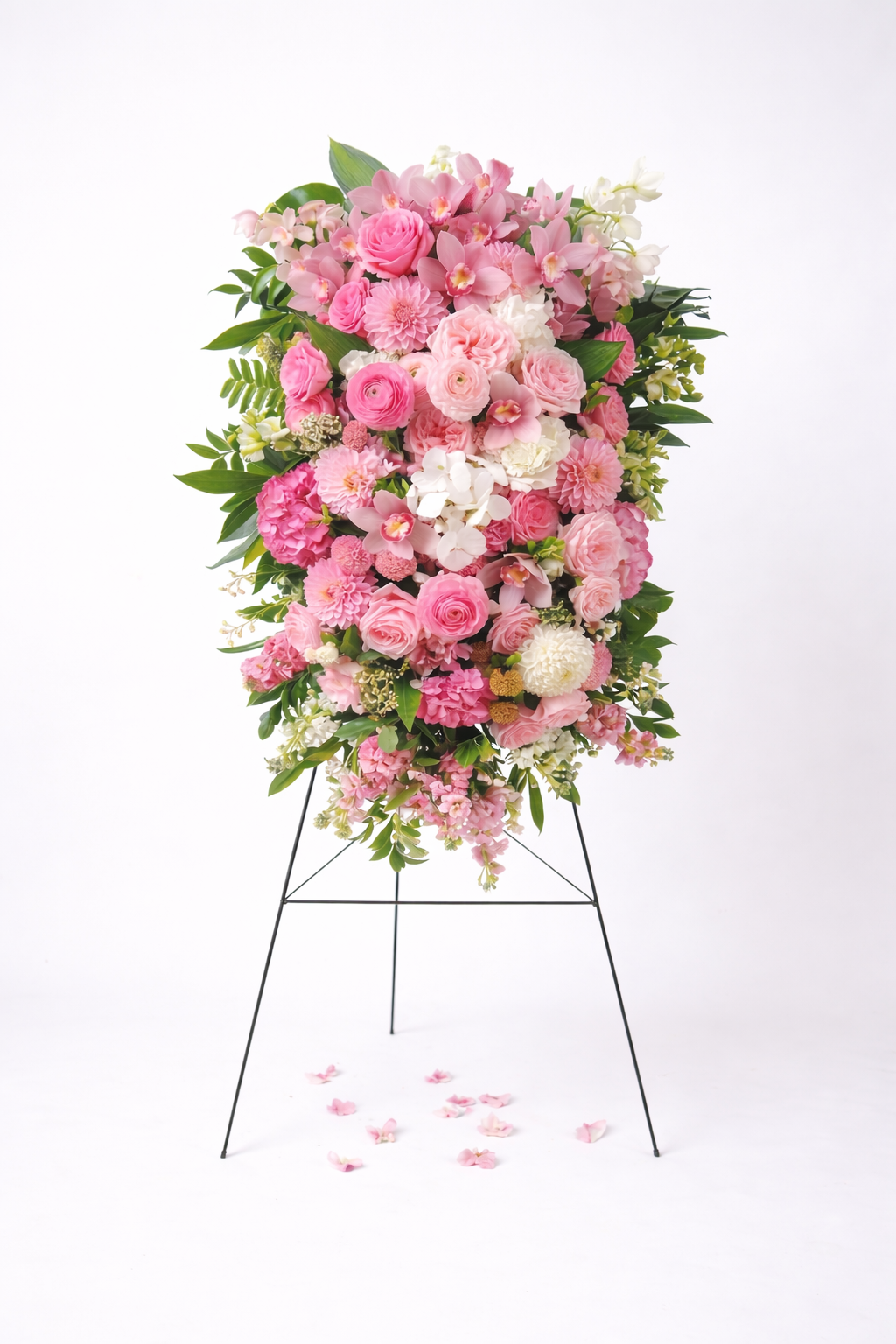 Pink sympathy standing spray with roses, orchids and seasonal flowers on easel