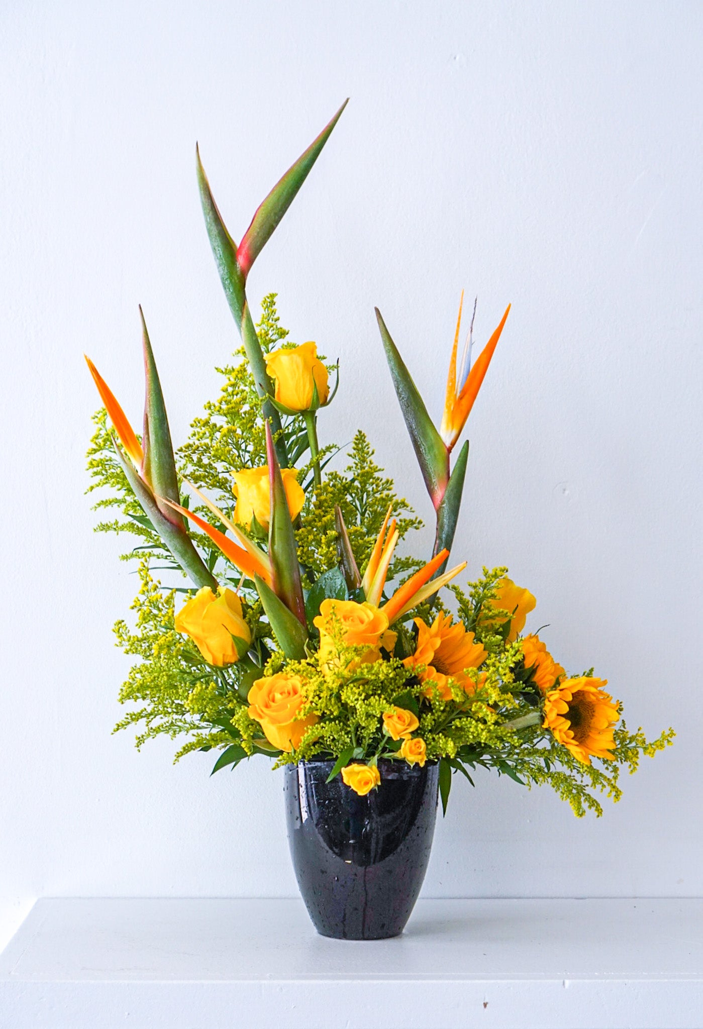 Send sun and paradise someone's way with this striking arrangement. We offer same-day and next-day delivery through out Toronto and GTA. This arrangement features Birds of Paradise, Sun flowers, Yellow Roses, Yellow Solidago