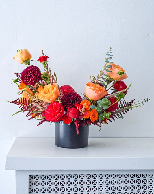 Mon Cheri is a perfect gift to your sweetheart. This arrangement has a bold colour palette of deep red, orange and touch of pink. Featuring local red garden roses, orange roses, dahlias, mini roses, and pink astilbe. 