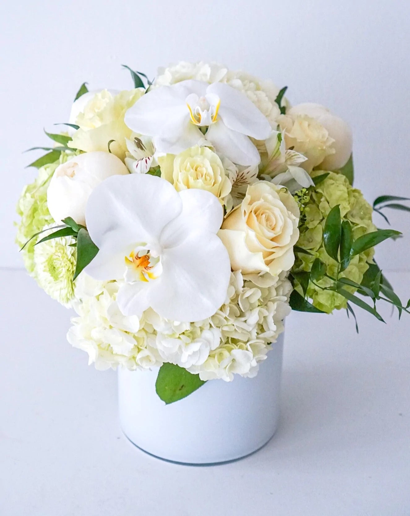 A combination of all premium blooms - Hydrangeas, Roses, with touch of Mini roses and Phalaenopsis orchid blooms, designed in a 5" x 5" cylinder glass vase
