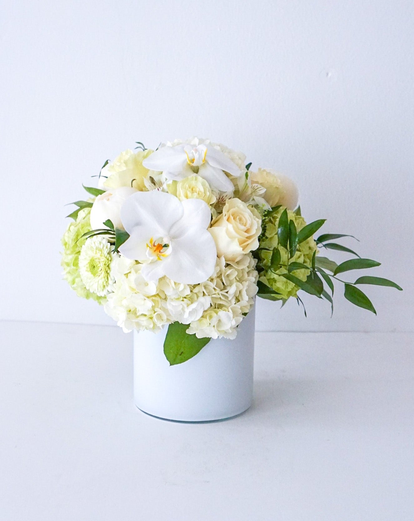 A combination of all premium blooms - Hydrangeas, Roses, with touch of Mini roses and Phalaenopsis orchid blooms, designed in a 5" x 5" cylinder glass vase