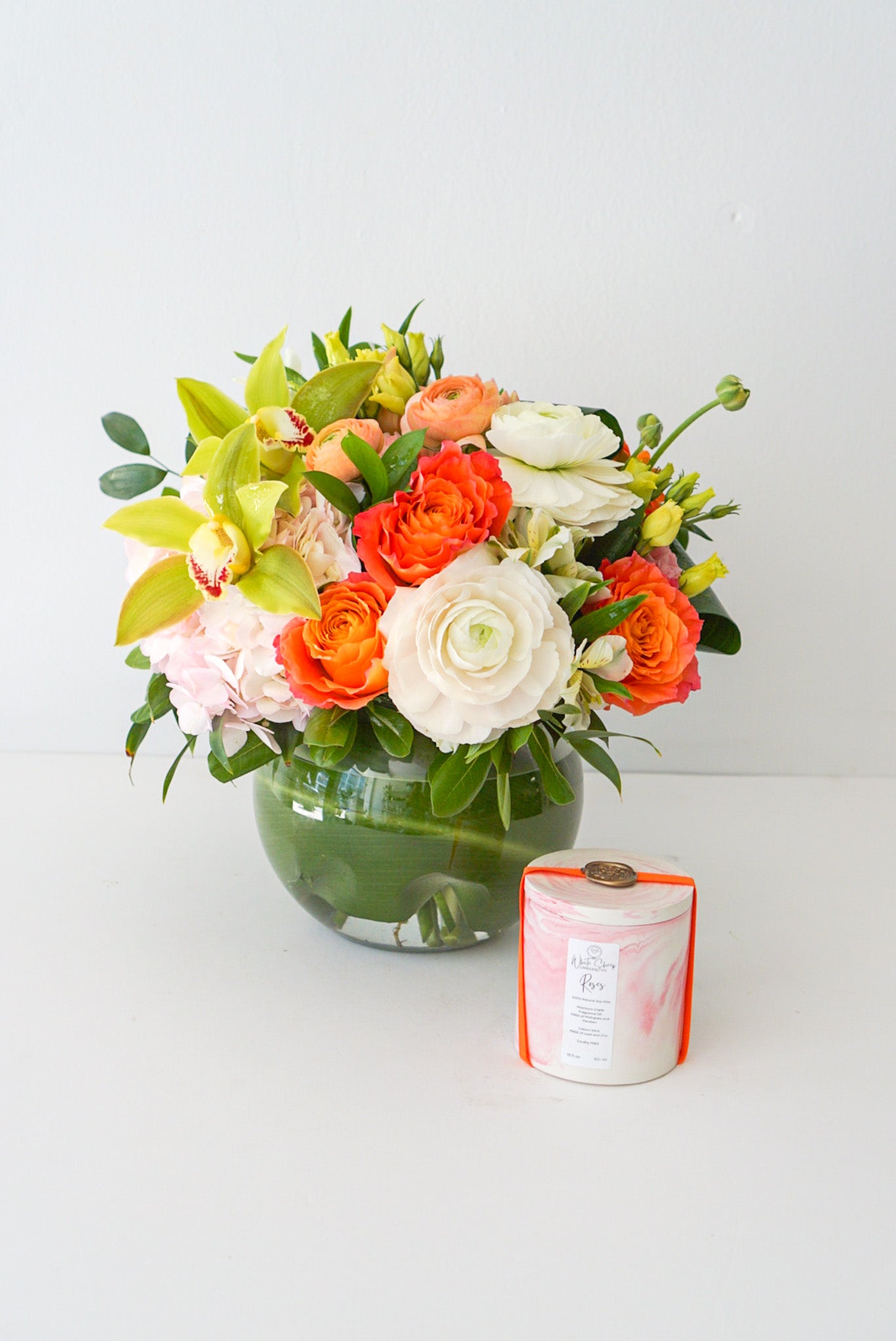 A fun-filled play on colours. The arrangement contracts pretty pink, peach, orange, green and white blooms with a fish bowl glass vase that sure to become multi purpose decor item. 