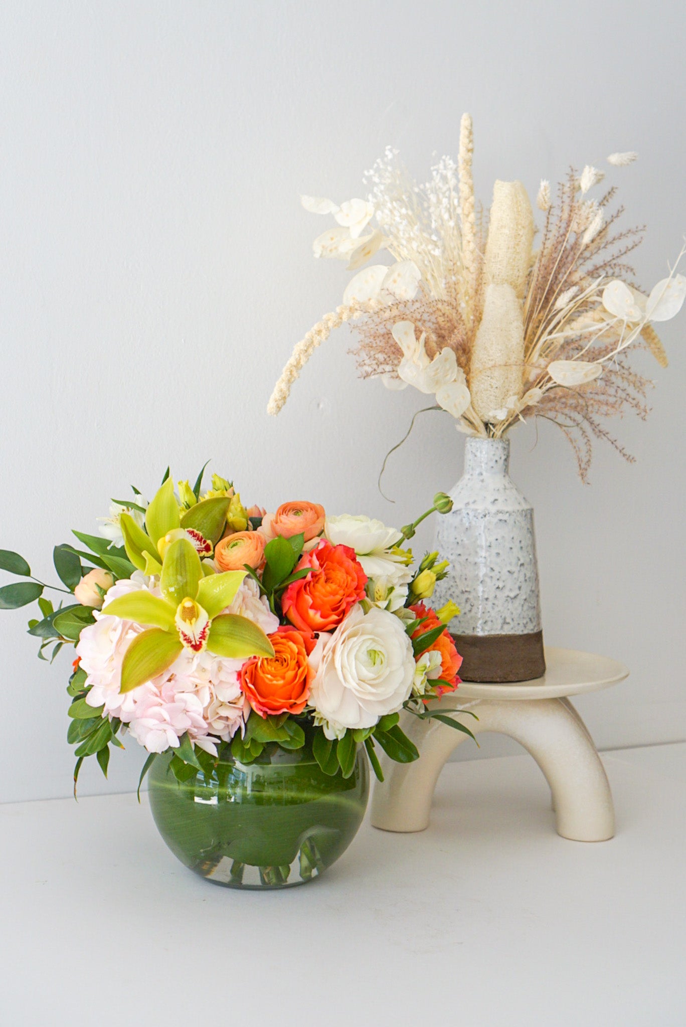 A fun-filled play on colours. The arrangement contracts pretty pink, peach, orange, green and white blooms with a fish bowl glass vase that sure to become multi purpose decor item. 